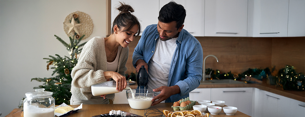 Image of male and female couple adding ingredients to a mixing bowl in the kitchen